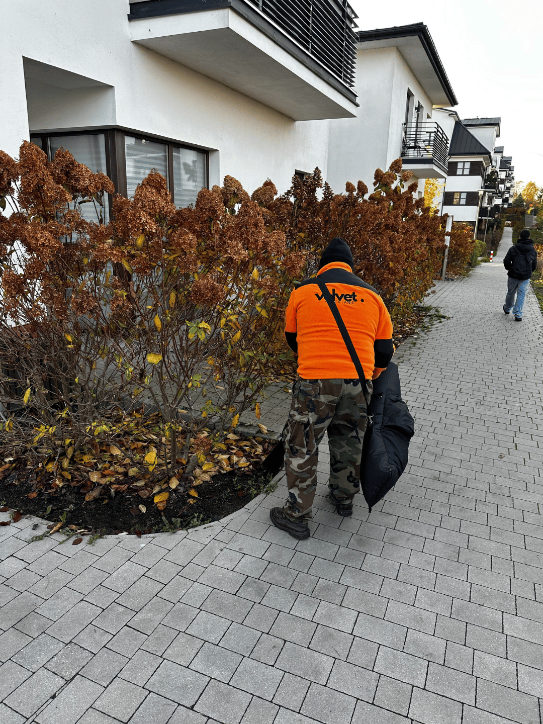 Pracownik Velvet Sprzątanie usuwa liście z rabaty na osiedlu